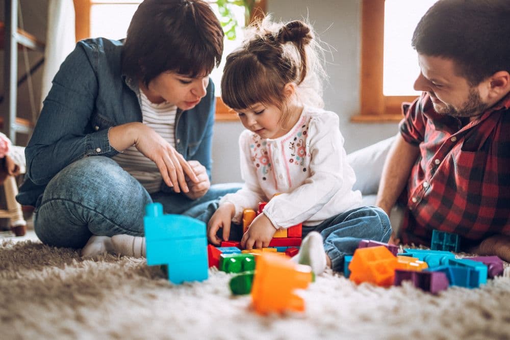 Family with young child playing with building blocks together